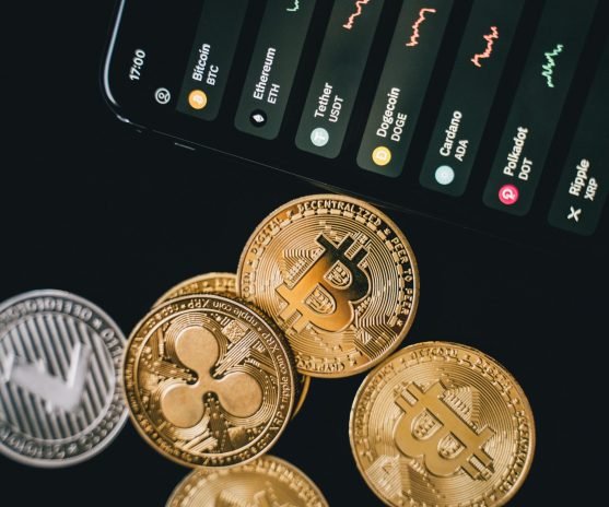 pexels-photo-6771664-6771664 Close-up view of various cryptocurrency coins with a digital market display in the background.